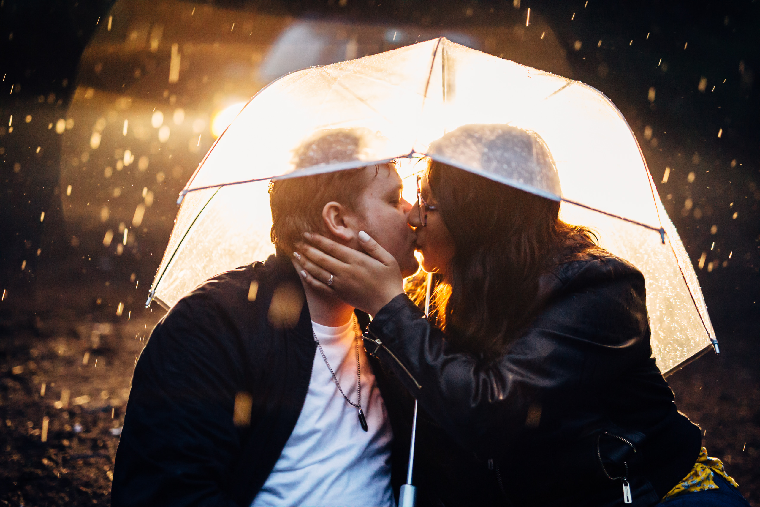 griffith observatory engagement photos Couple kissing underneath umbrella at night with rainfall.