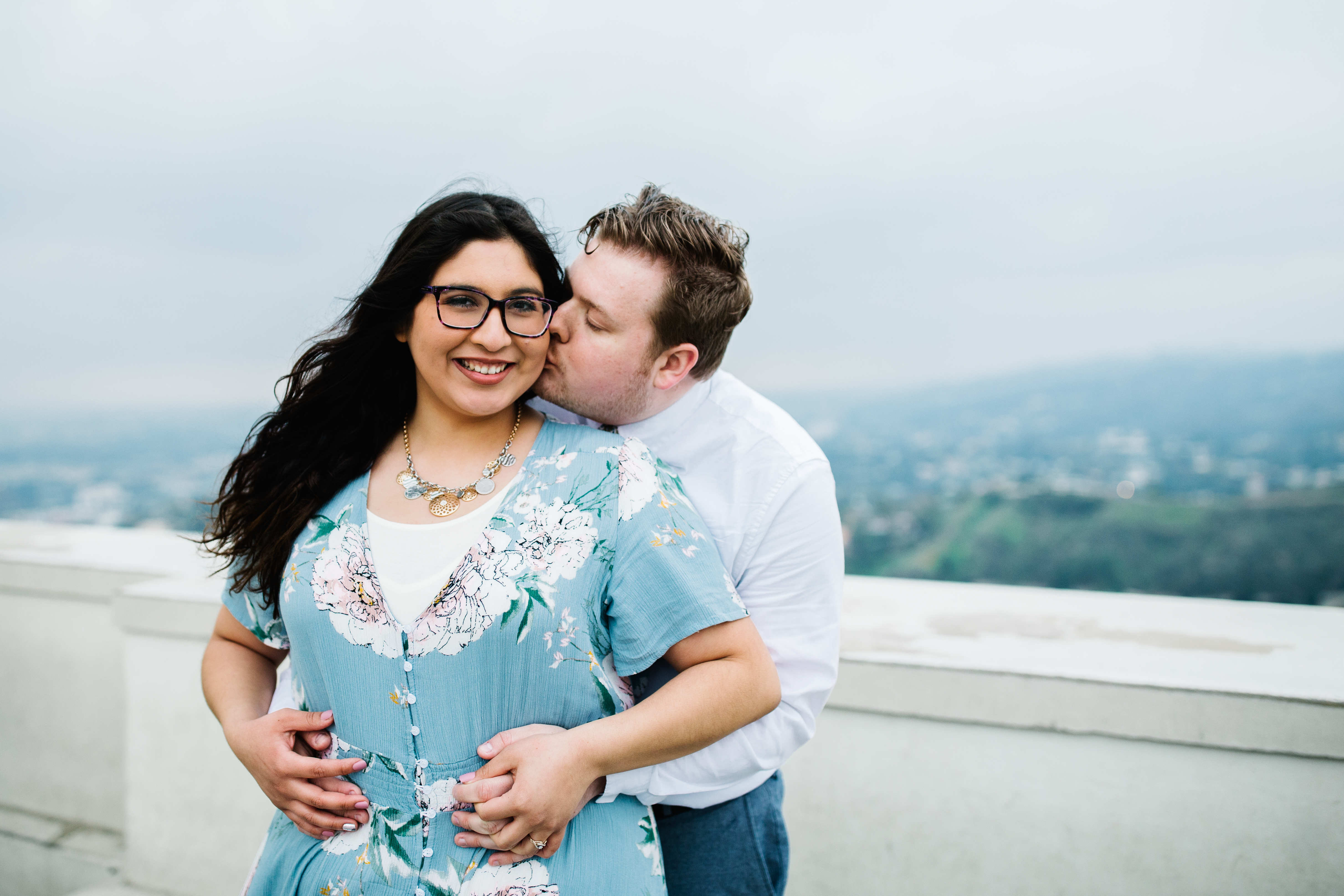 griffith observatory engagement photos Man kisses woman's cheek at Griffith Observatory in Los Angeles , California.