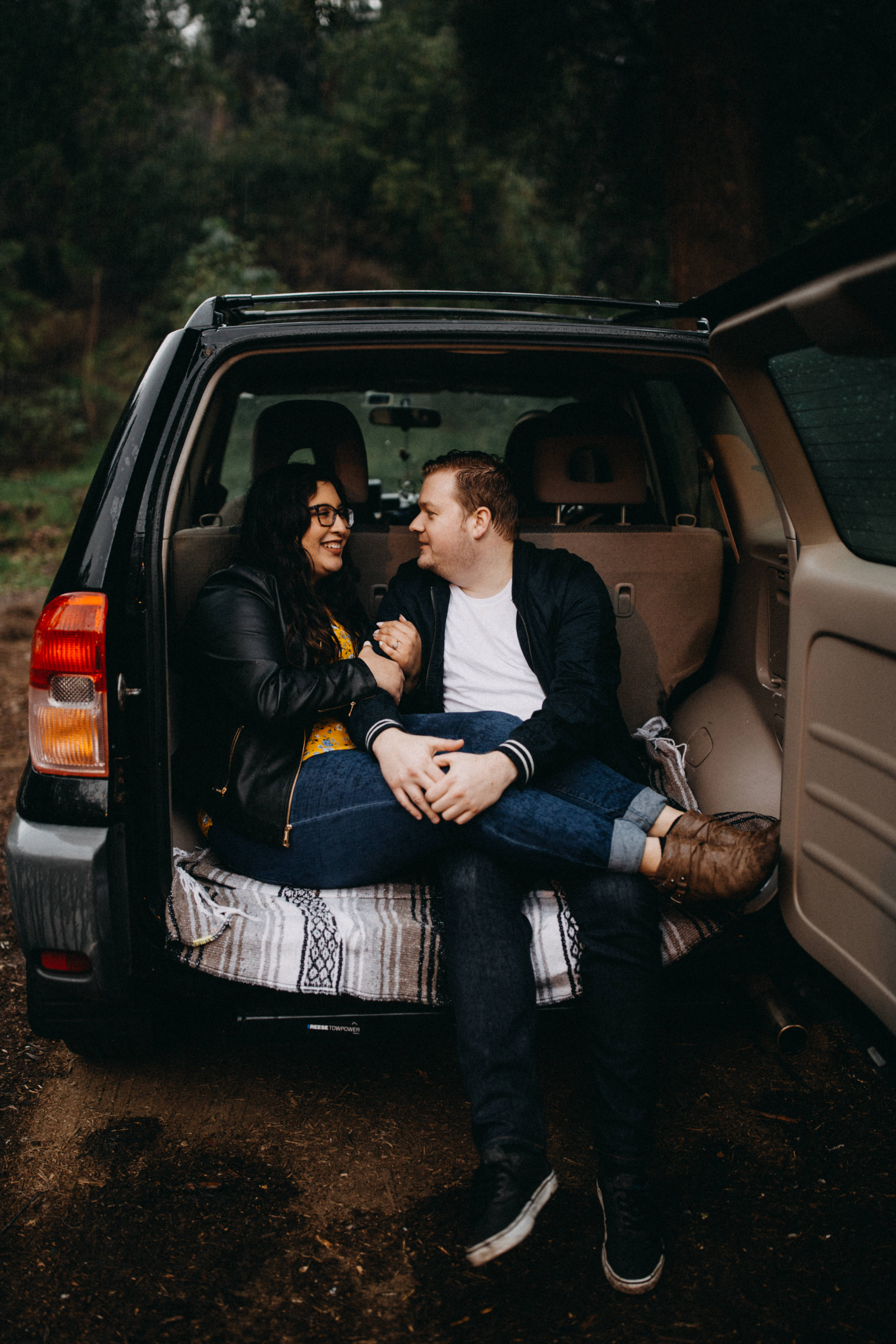 griffith observatory engagement photos Couple sits in the back of a Toyota Rav 4 on a rainy day.