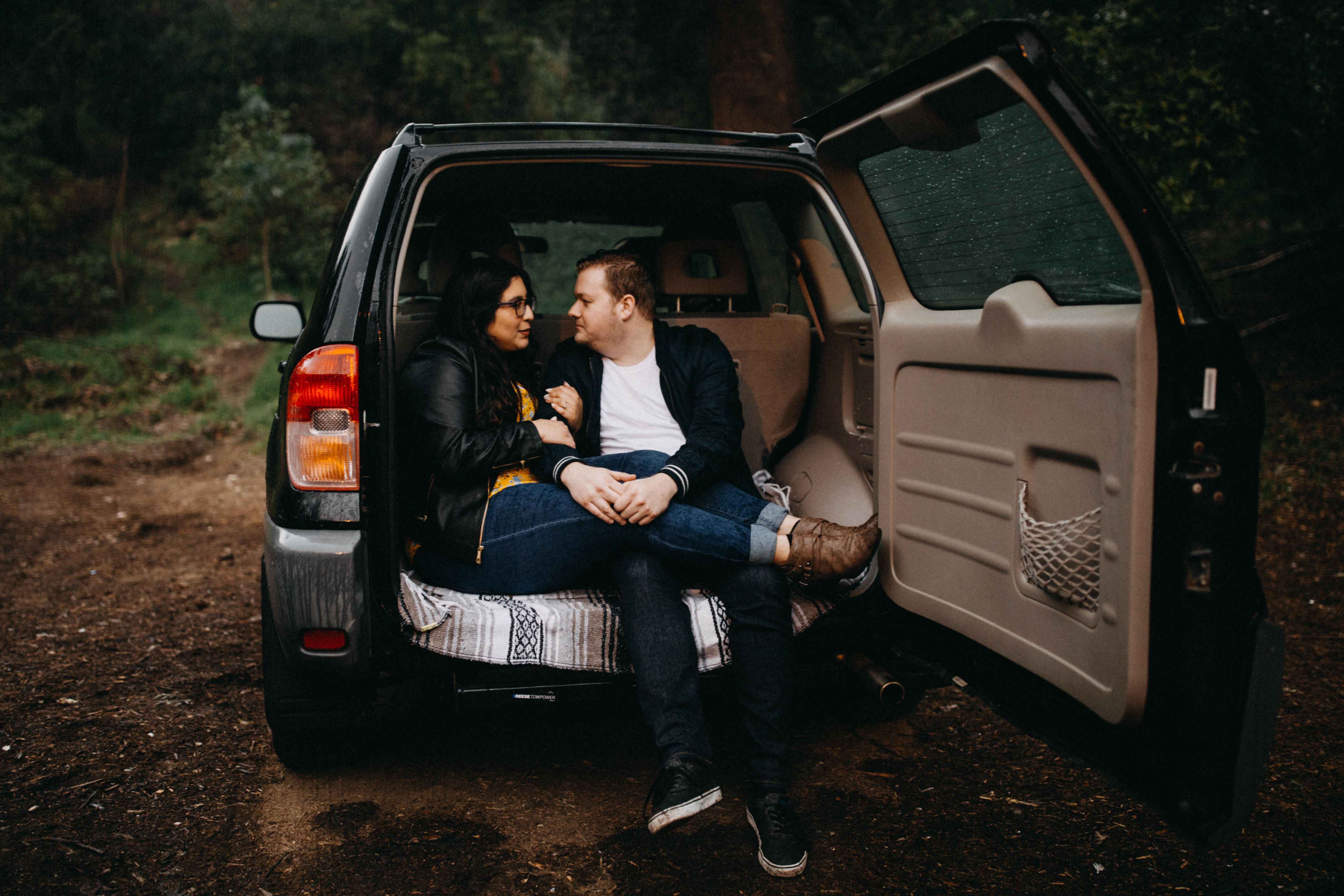 griffith observatory engagement photos Couple sitting in the back of a Toyota Rav 4 on a rainy day.