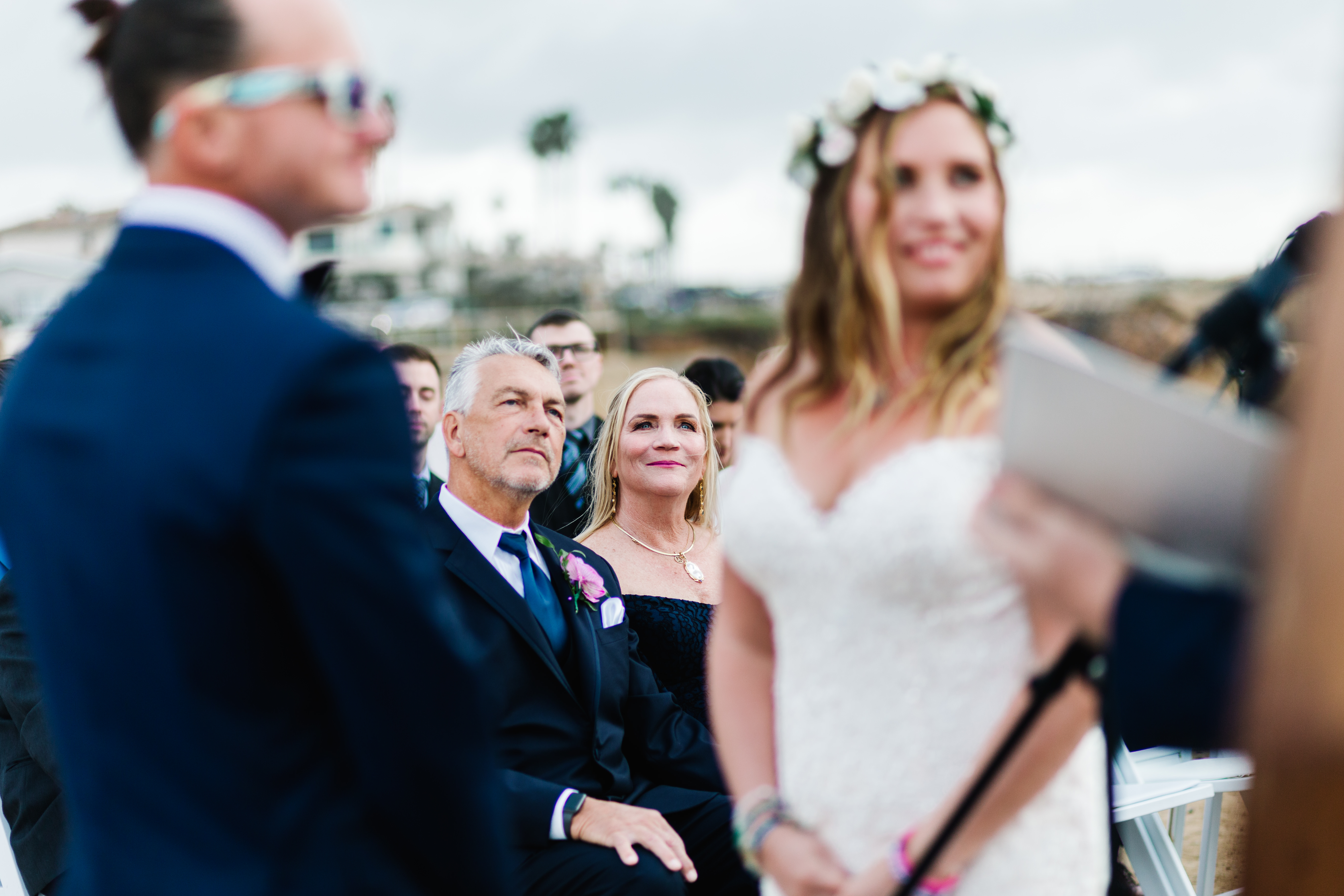 parents of bride looking lovingly at couple at sunset cliffs wedding