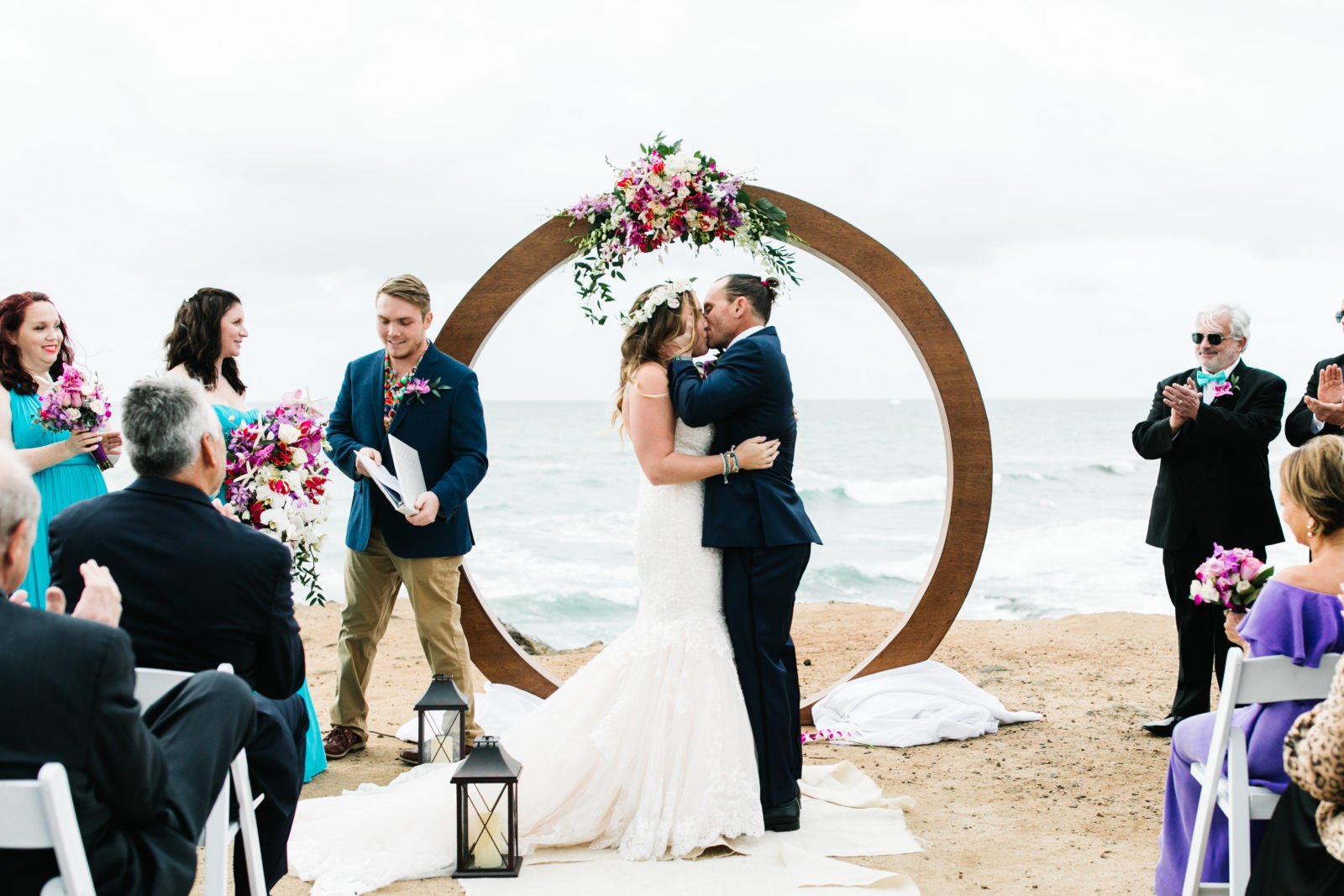 bride and groom kissing at altar with circular arch at sunset cliffs wedding
