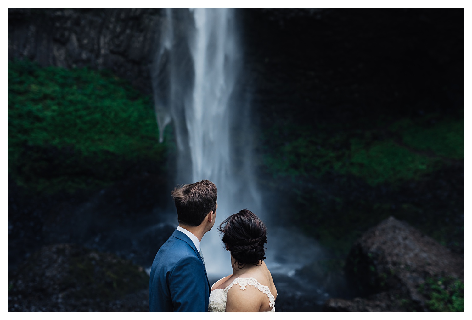 bride and groom looking at waterfall