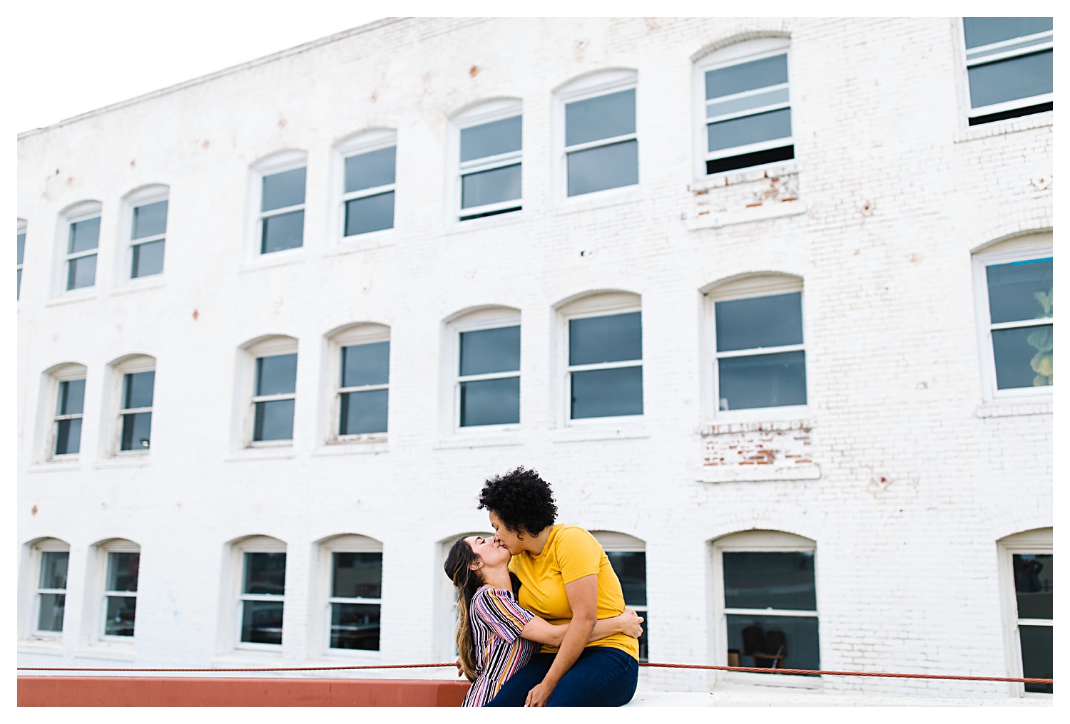 couple kissing with white building in background