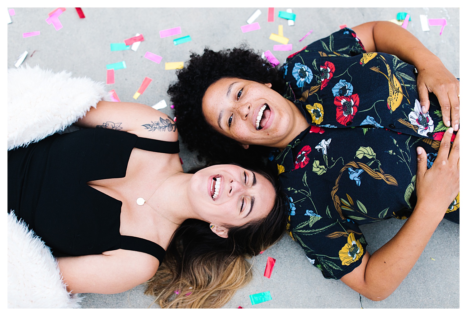 couple laughing laying down in confetti