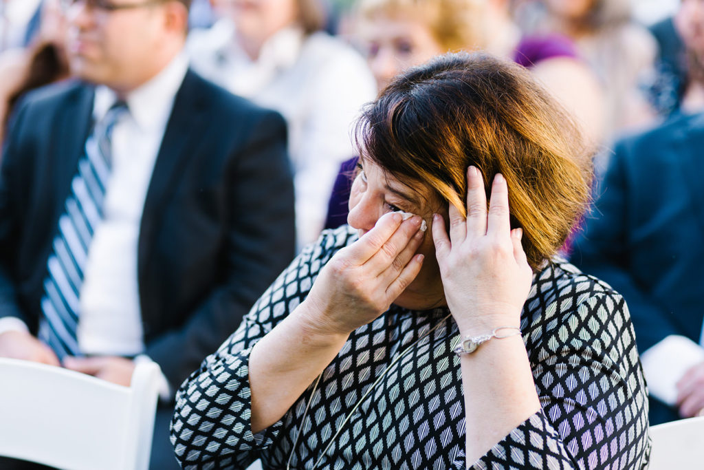 wedding guest wipes tear from her eye