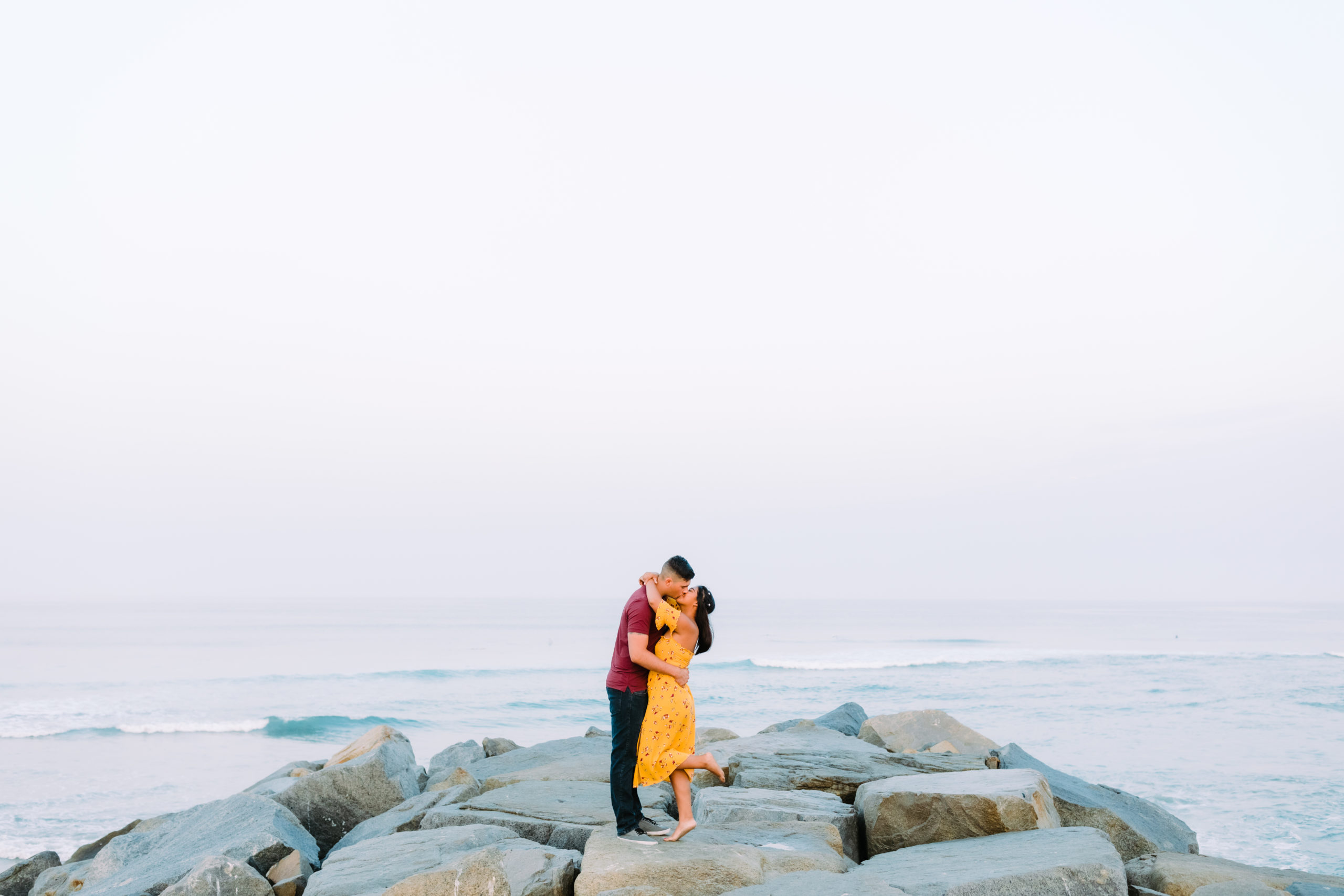 couple kissing with ocean in the background
