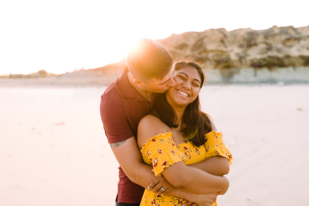 man hugging woman on beach at sunrise